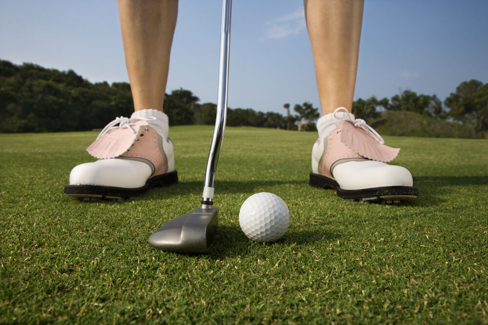 Golfer putting with the ball just forward of center