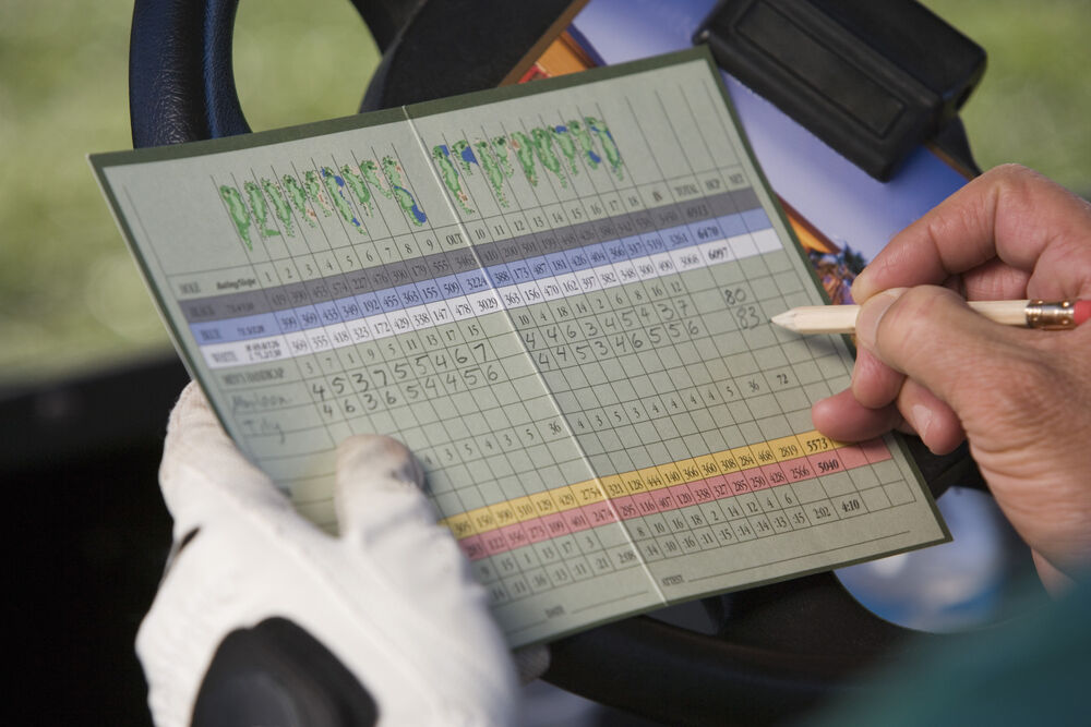 Golfer writes scores on a scorecard