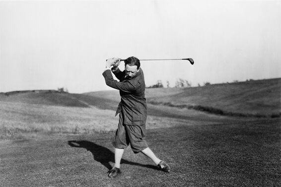 Old time photo of a man playing golf