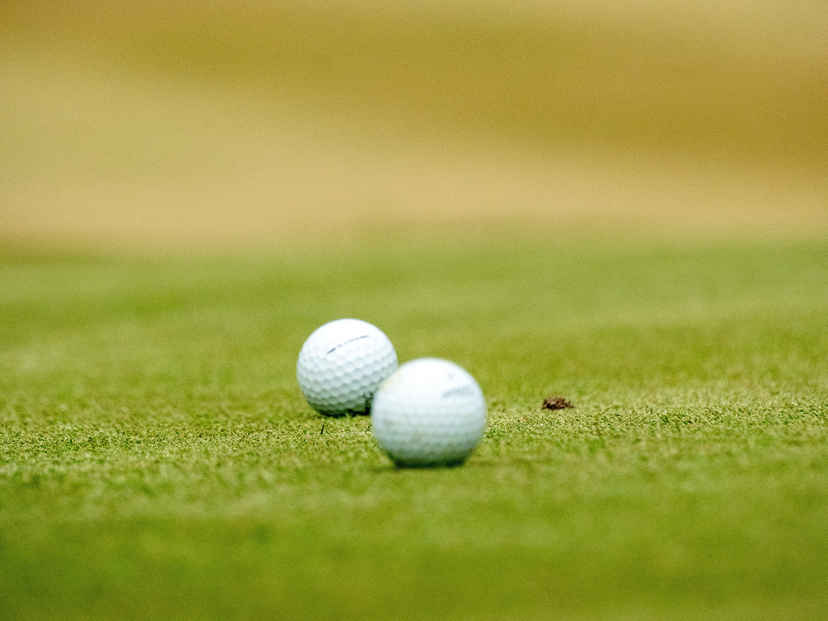 Two golf balls at rest on the putting green