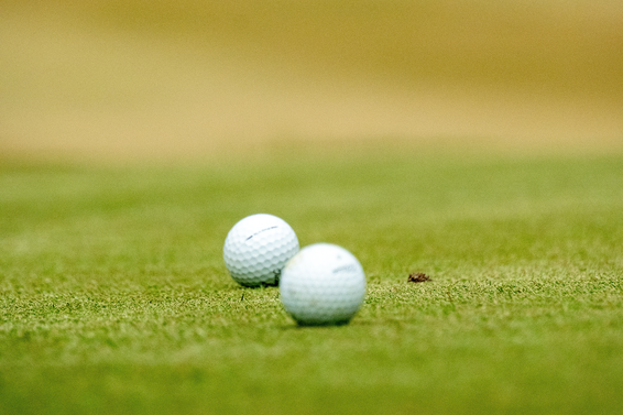 Two golf balls at rest on the putting green