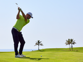 Golfer at the top of his swing with iron