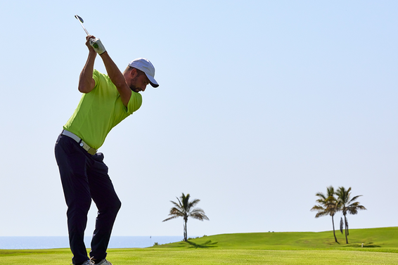 Golfer at the top of his swing with iron
