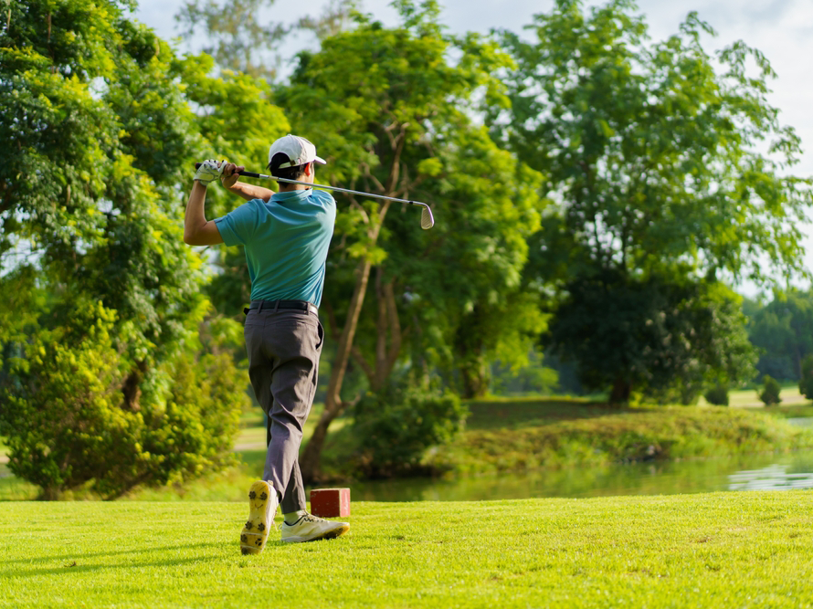Golfer hitting a long iron over water