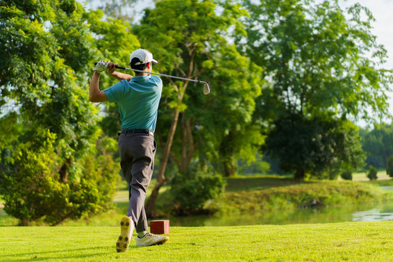 Golfer hitting a long iron over water