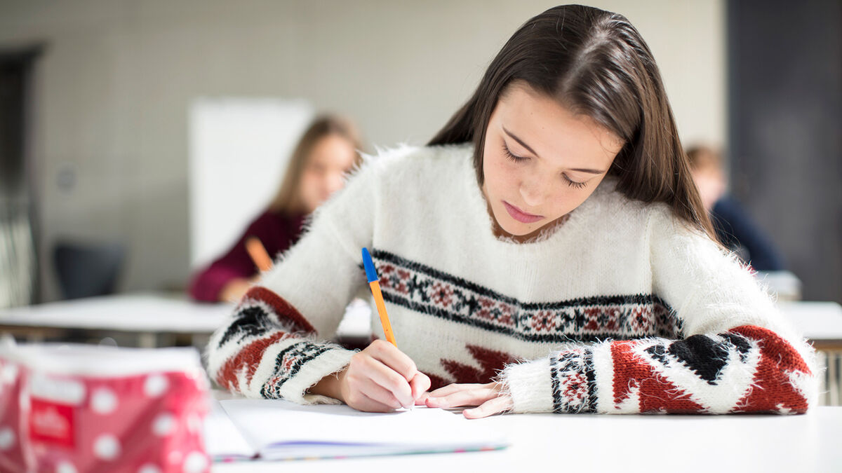 Girl writing expository essay in class