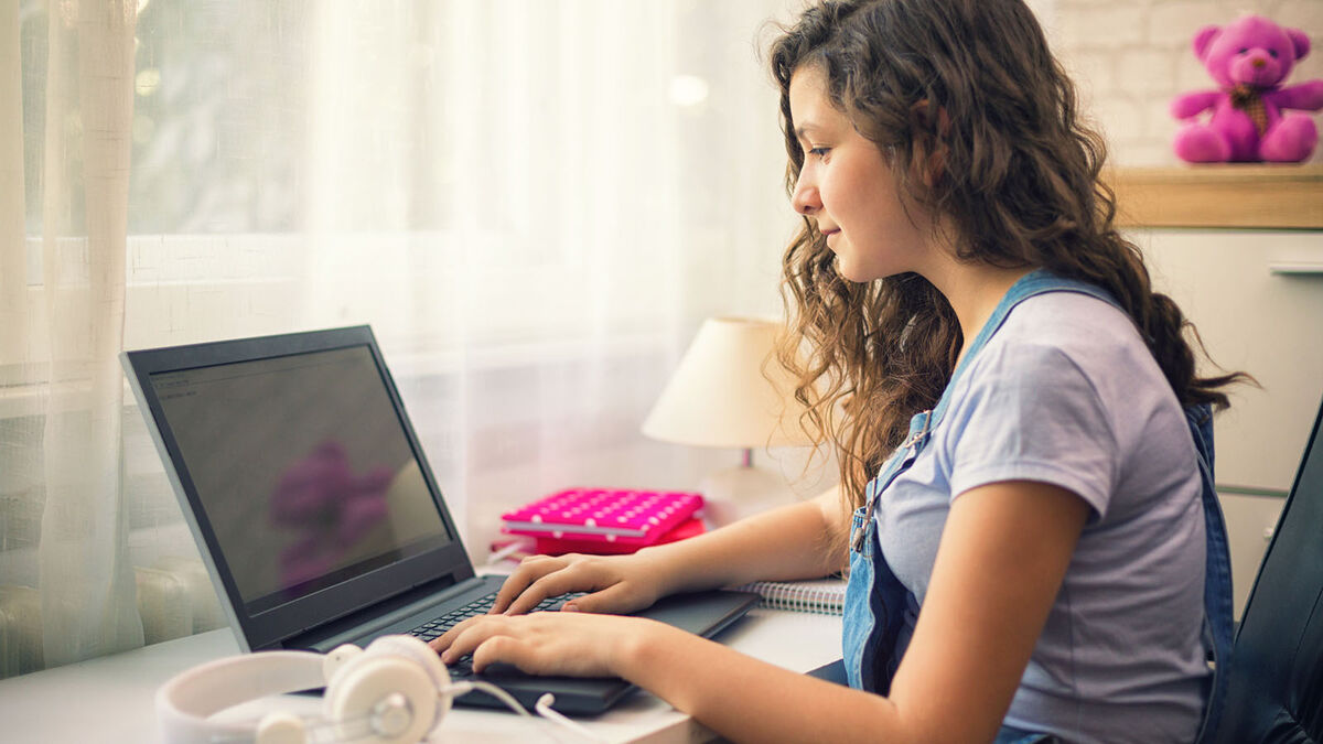 Teenager typing essay on laptop computer