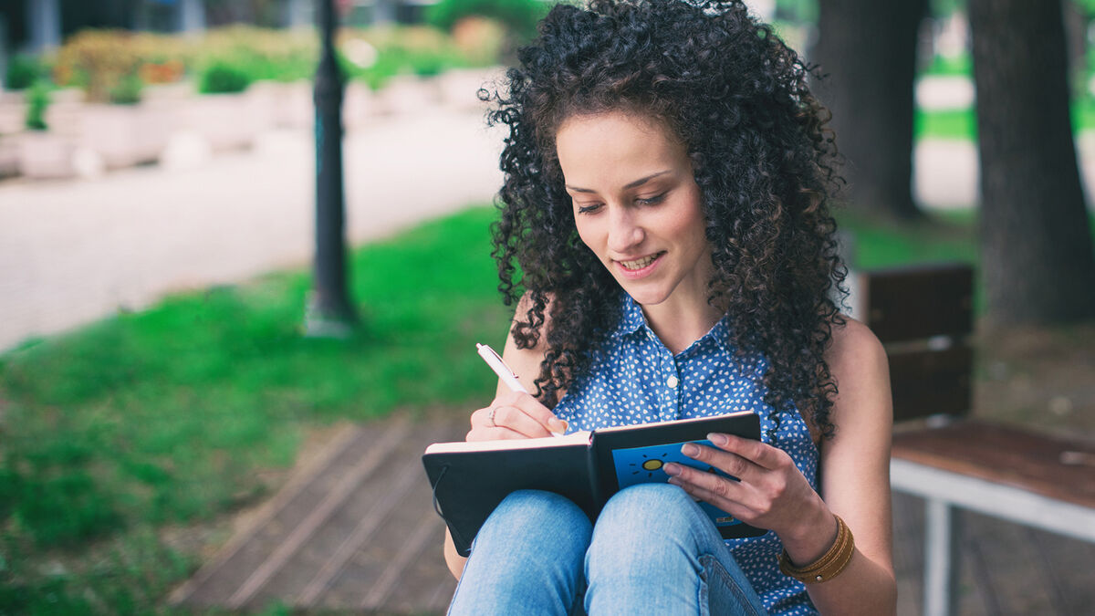 woman writing ballad poem in journal