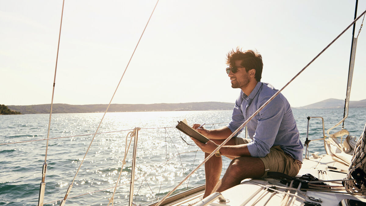 man writing ballad on boat in journal