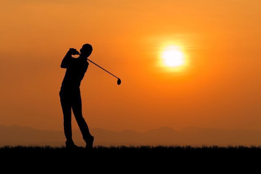 golfer hitting with sunset background