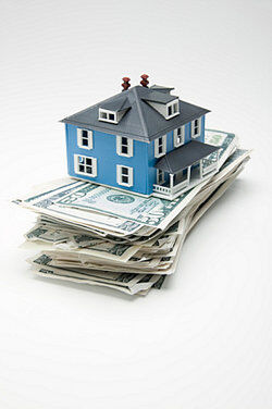 Model house on a stack of dollar bills as examples of assets