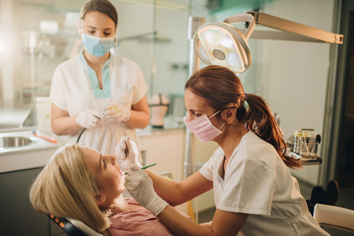 Dentist and dental assistant examining woman's teeth