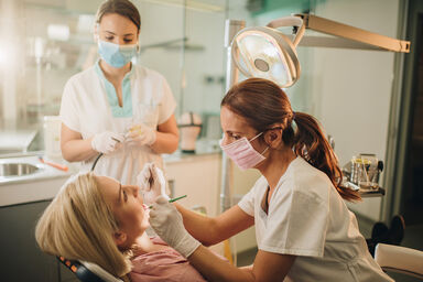 Dentist and dental assistant examining woman's teeth