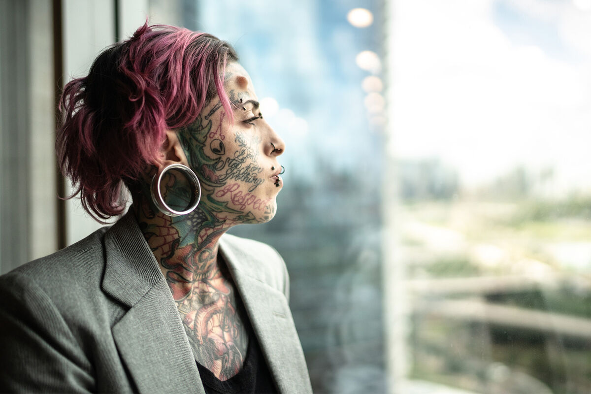 Tattooed  woman looking out of window