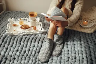 Woman in woolen socks and sweater sitting on wool chunky blanket
