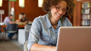 young woman typing on laptop in library