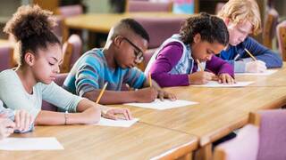 elementary school students writing at desks