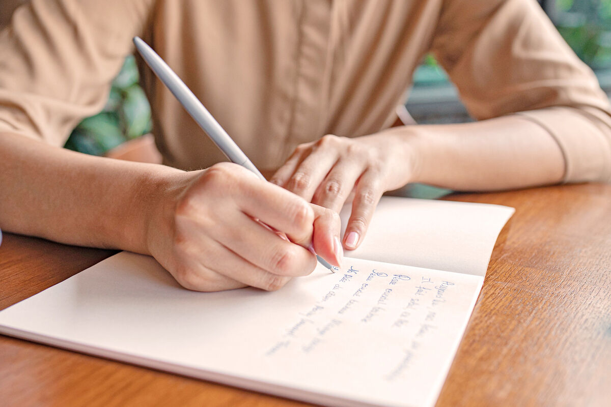 Woman's Hands Writing Notes in a Notebook