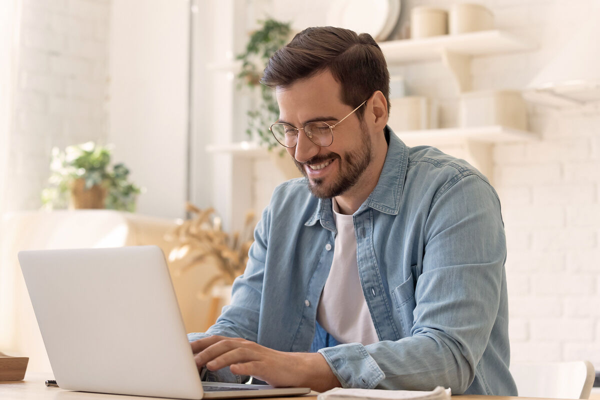 Smiling young man using laptop at home