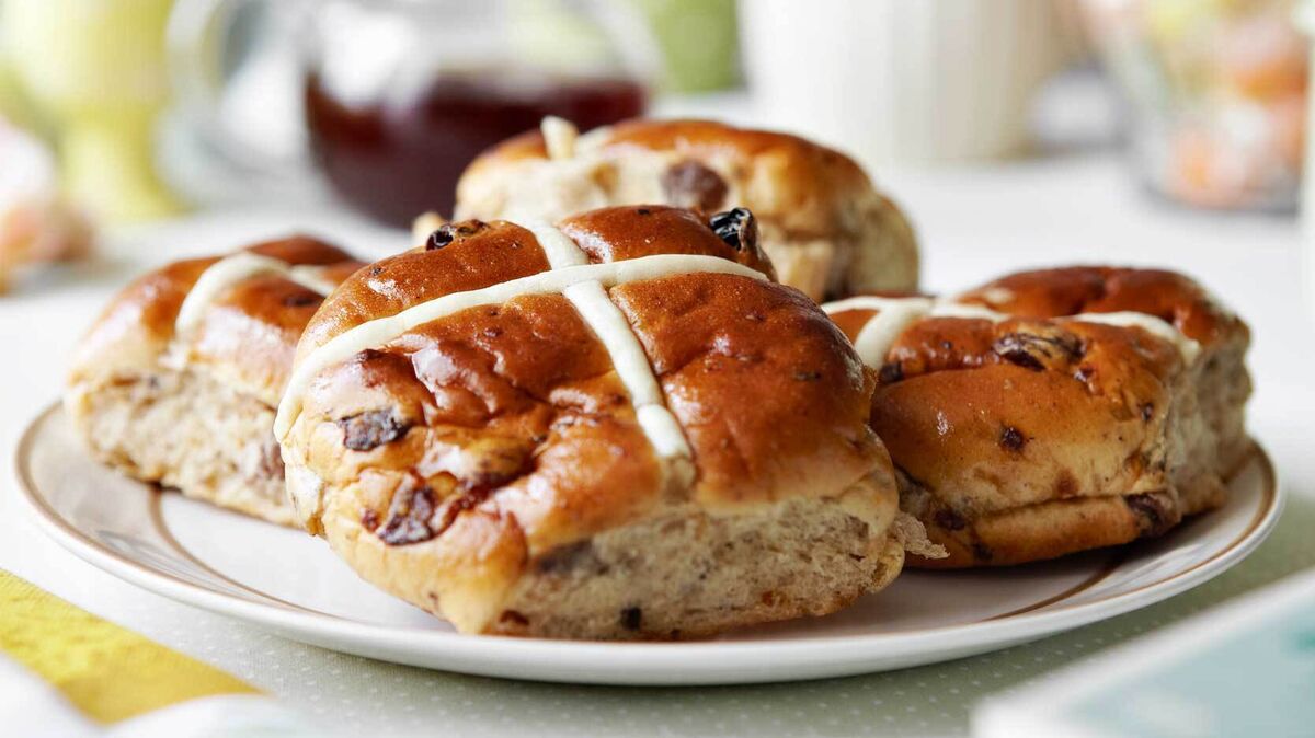 Hot cross buns stacked on a plate.