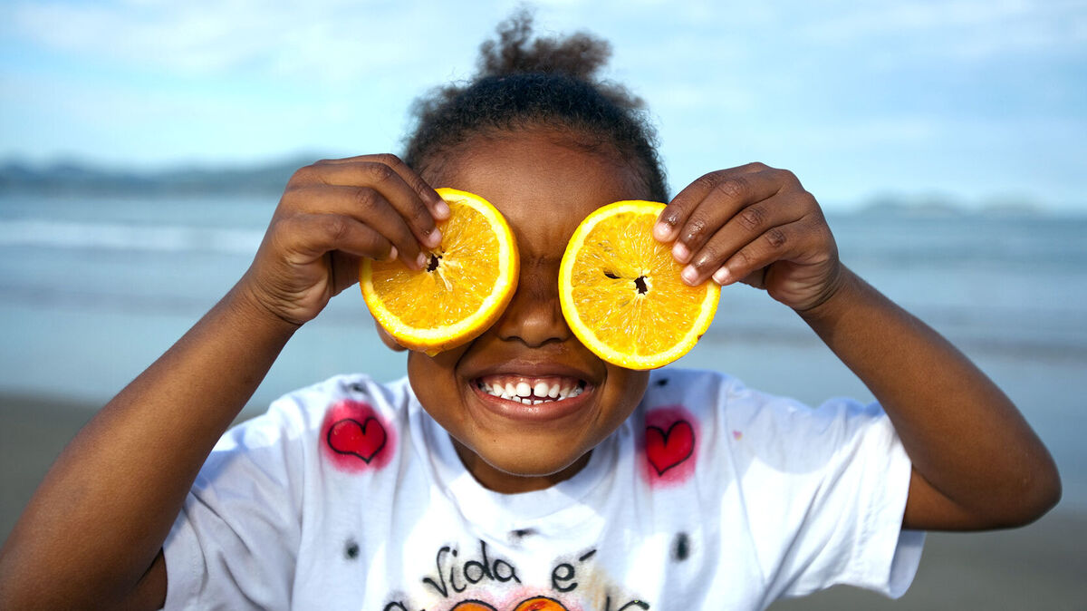 girl holding Florida orange slices over eyes