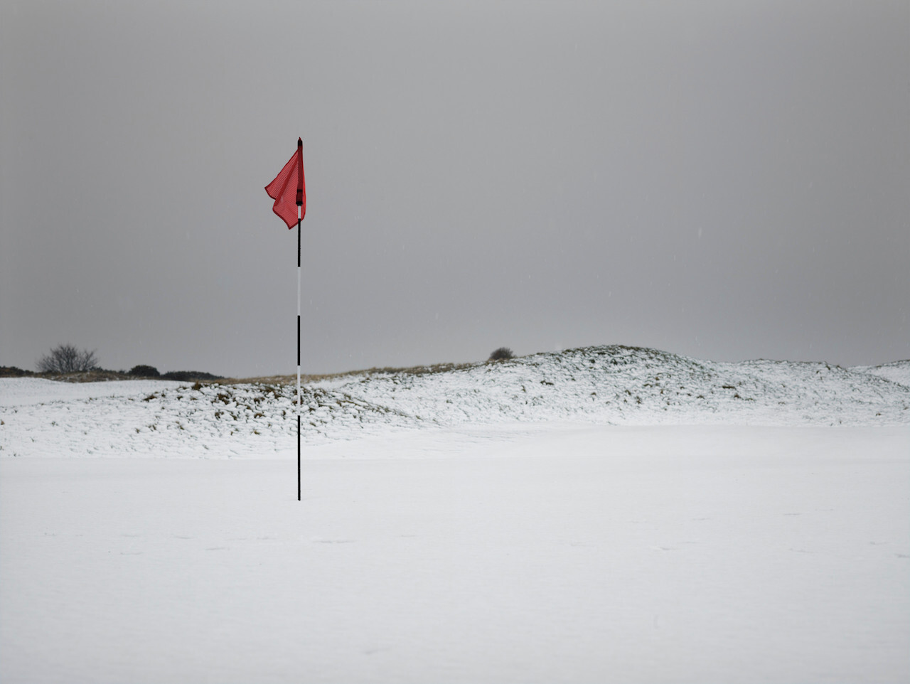 Red golf flag on snowy course
