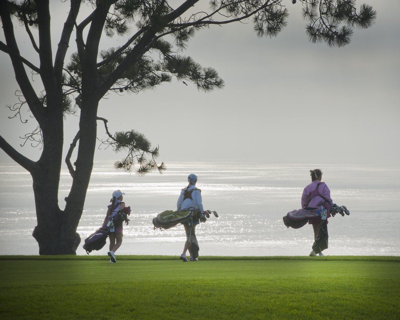 Girls carrying golf bags on course