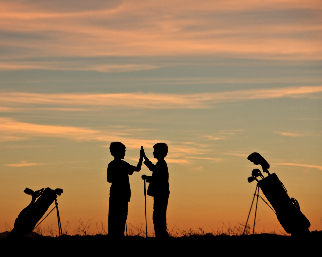 Young golfers highfive with clubs