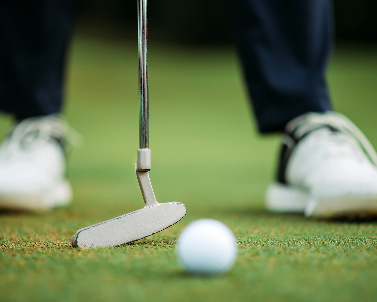 golfers feet with putter and ball