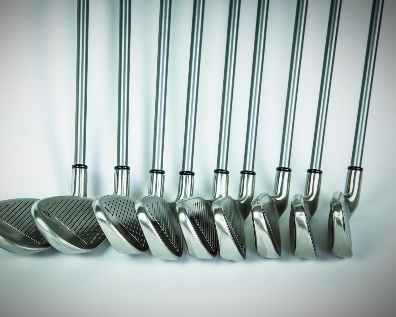 Golf clubs in row gray background