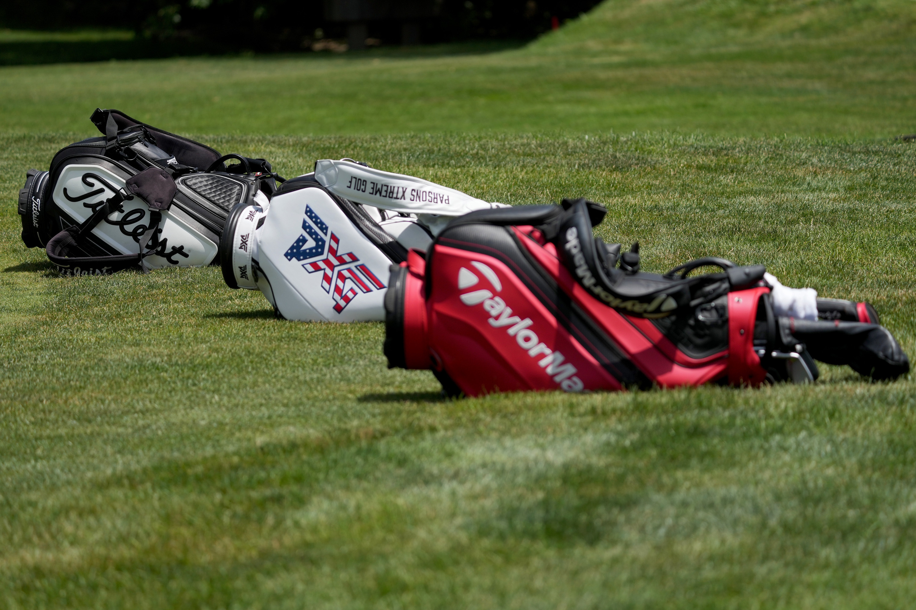 Three golf bags on ground at tournament