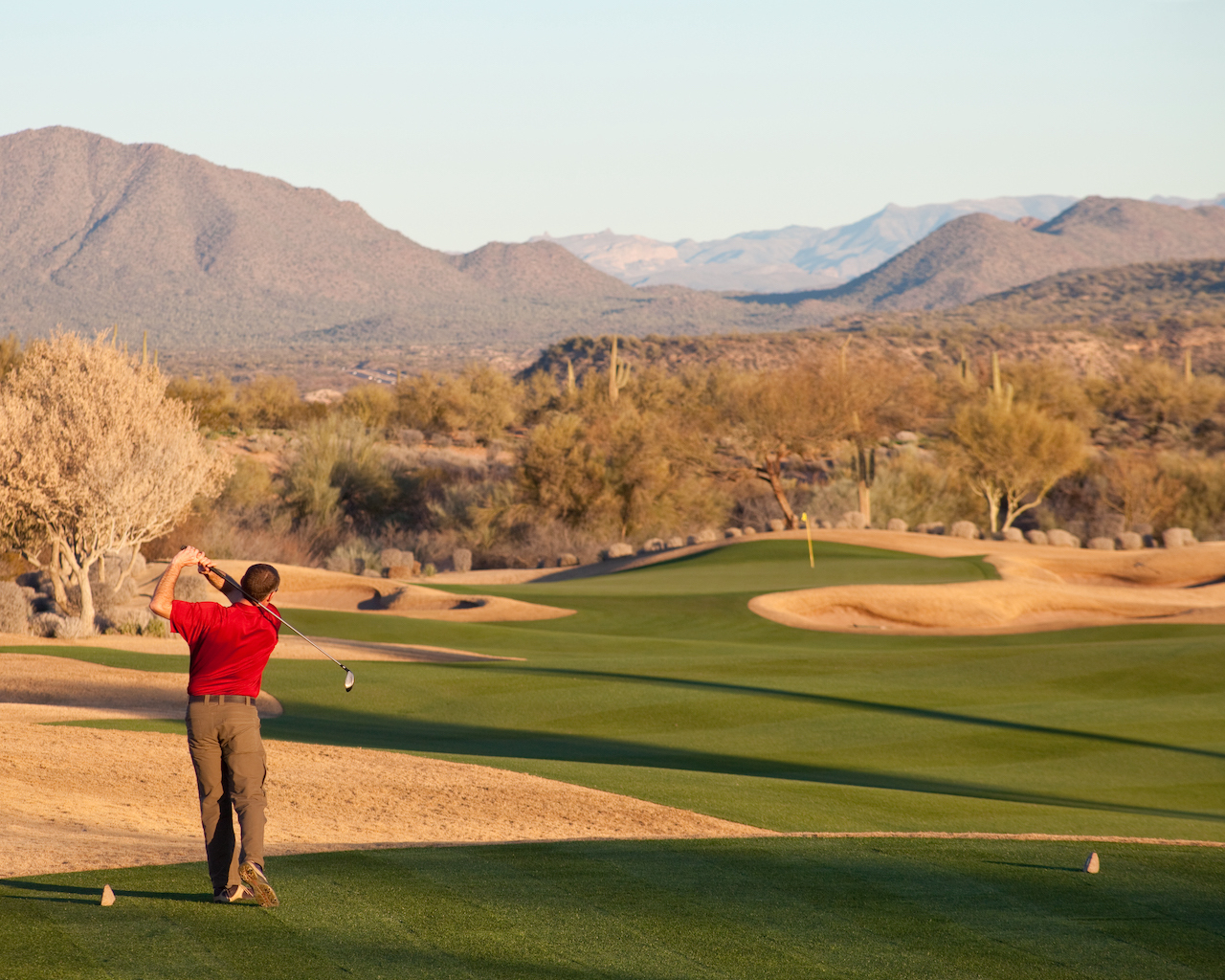 golfer teeing off on desert course