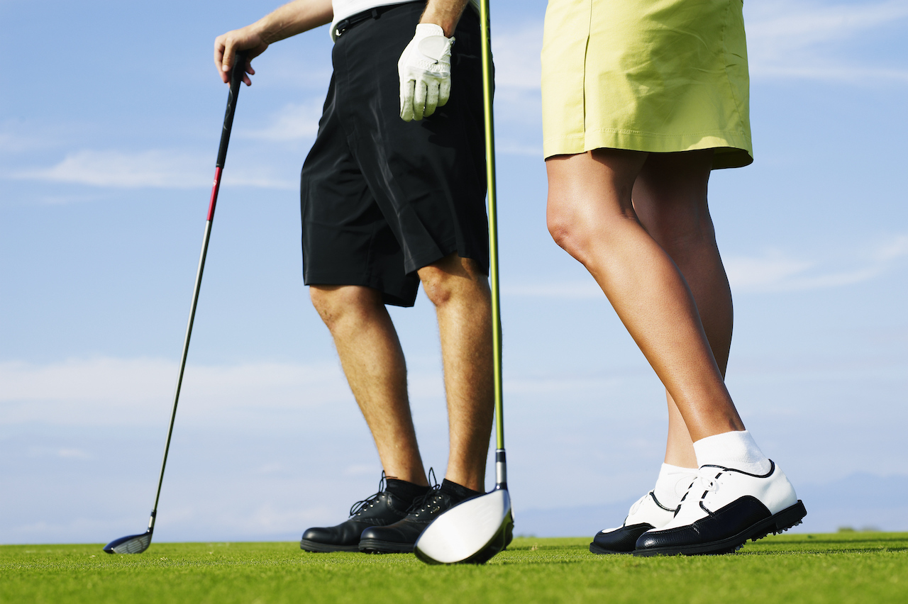 Two golfers wearing shorts with clubs