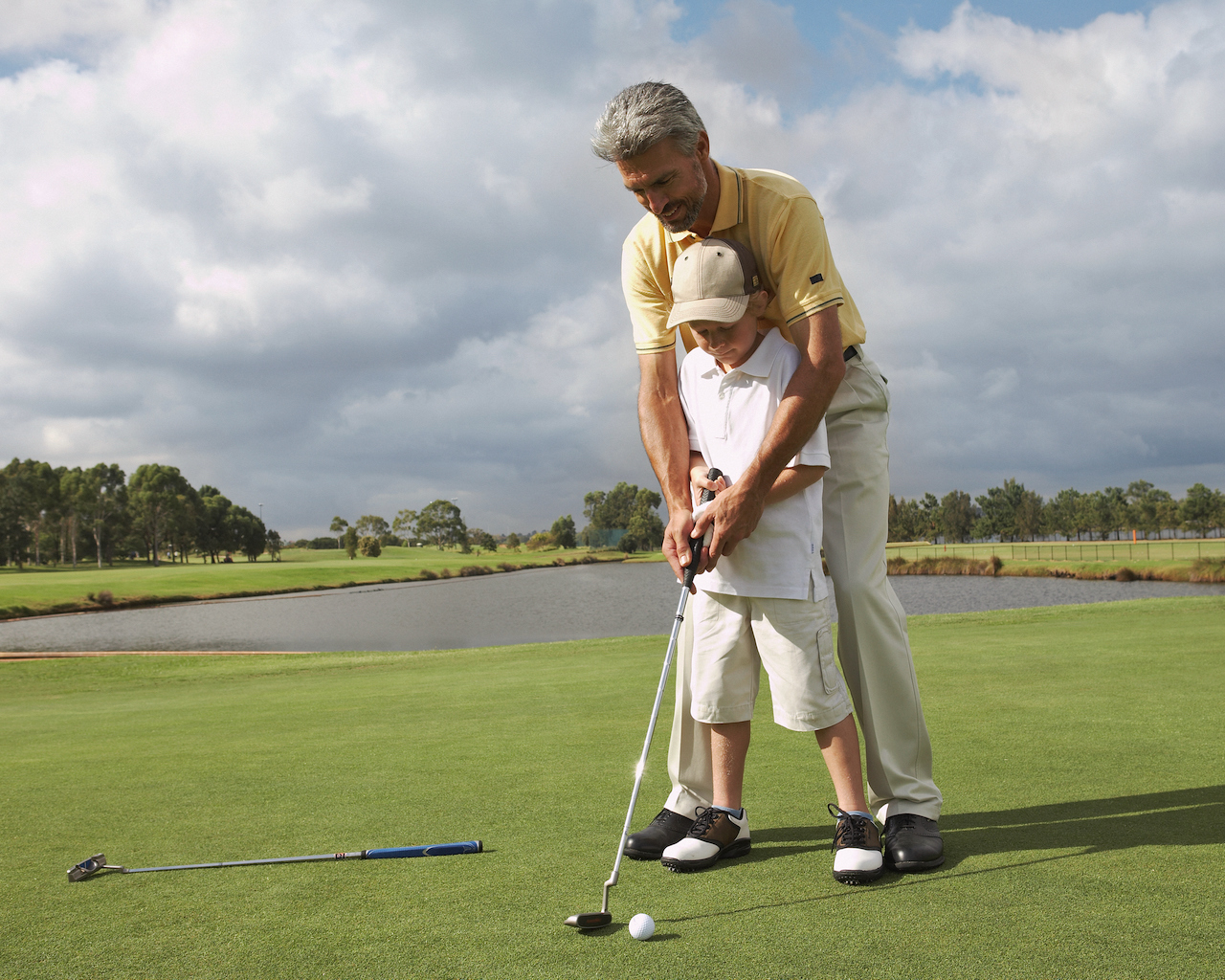 Man helping grandson with putter