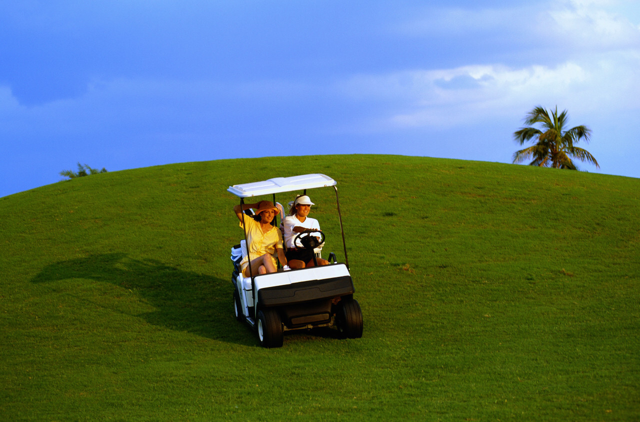 two women driving golf cart downhill