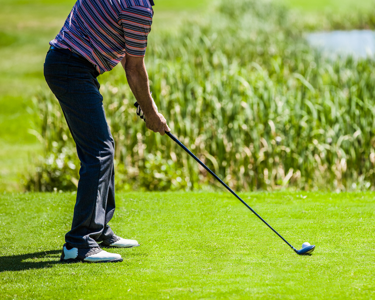 golfer addressing ball with hybrid club