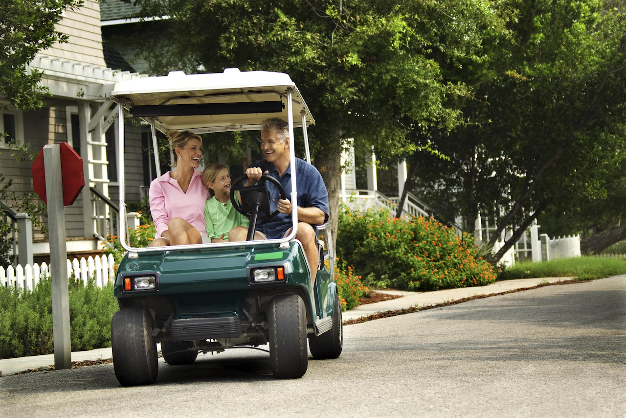 family in golf cart on street
