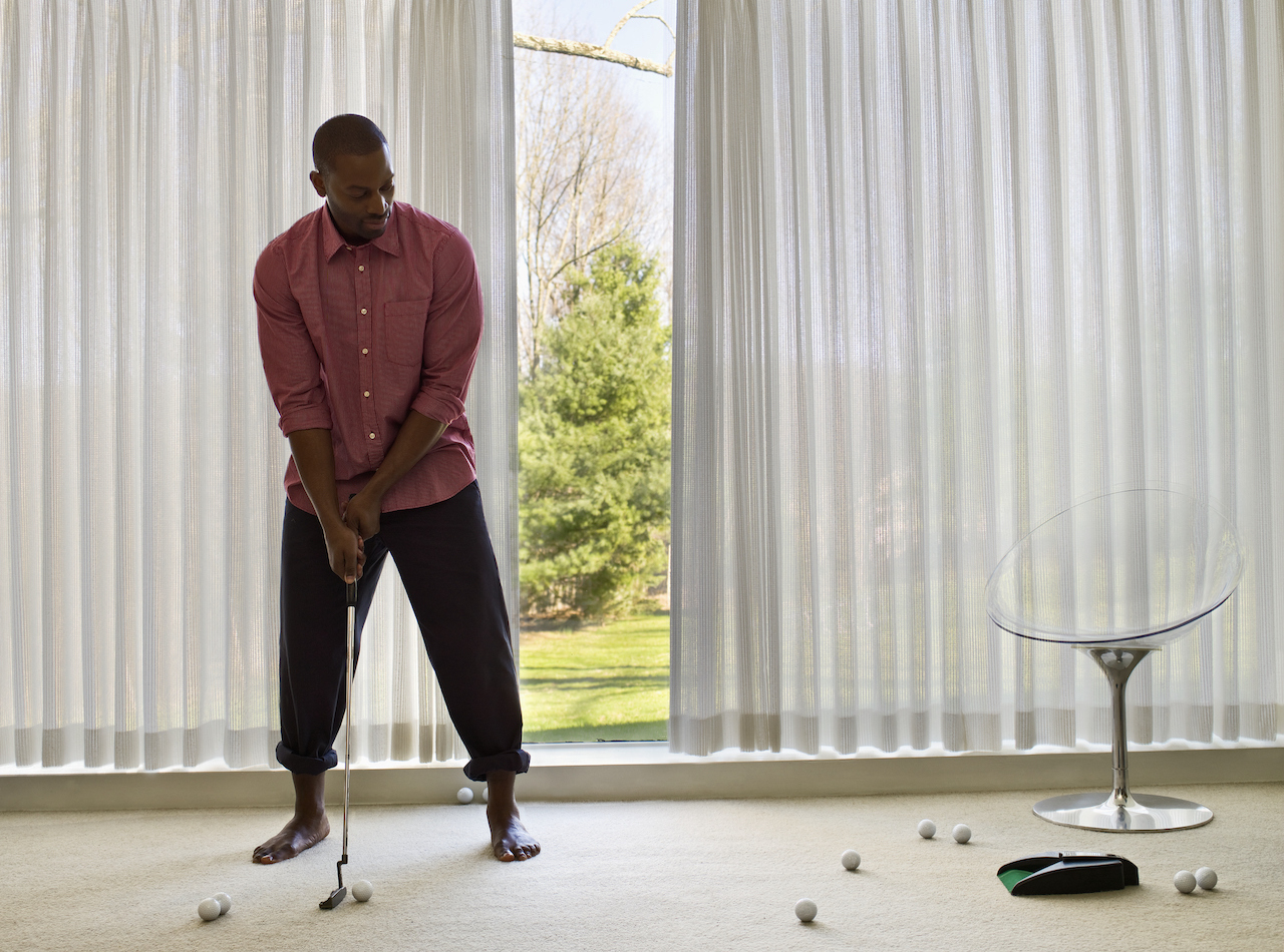 man practicing putting at home