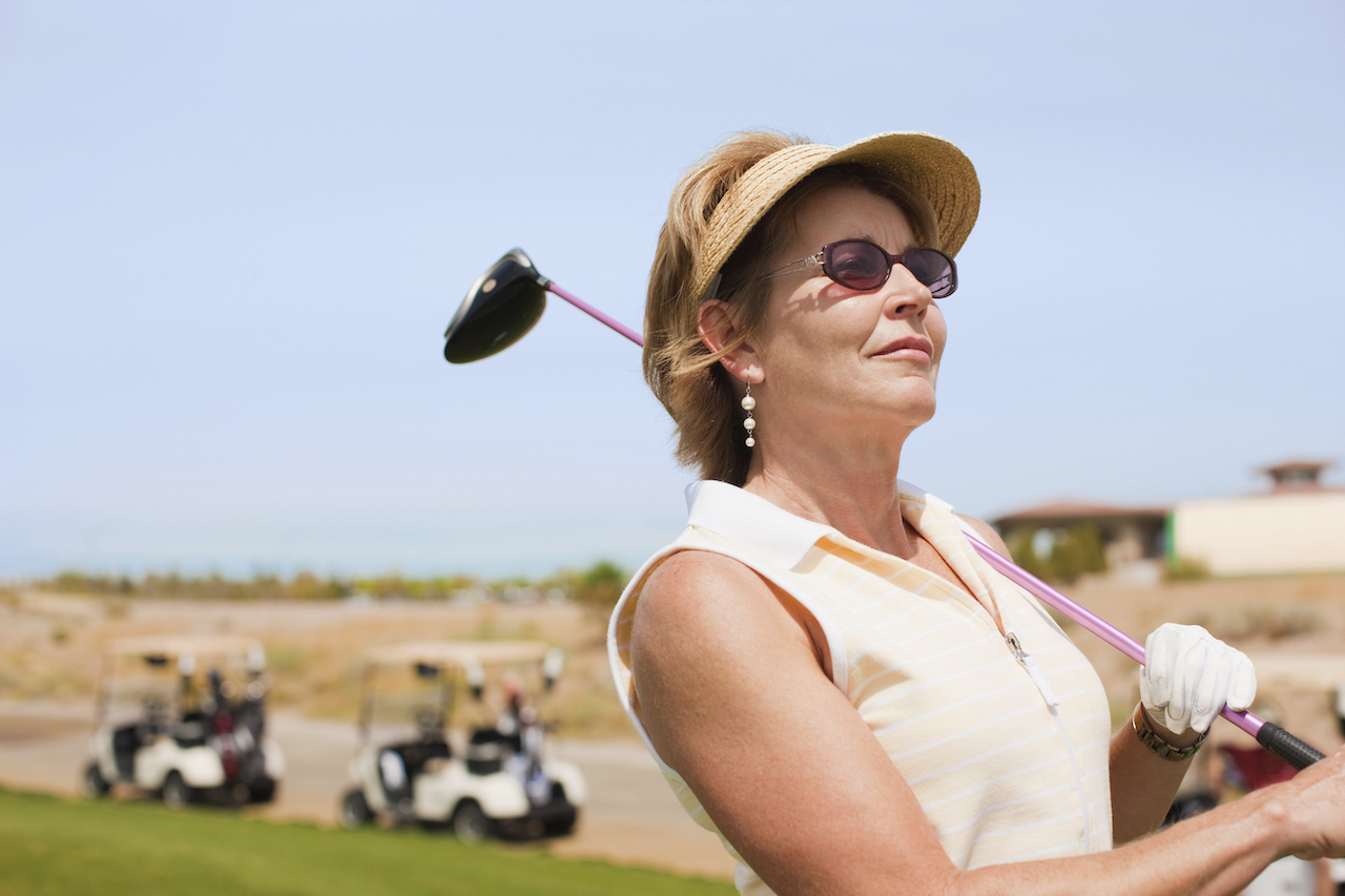 Golfer wearing sunglasses watching shot