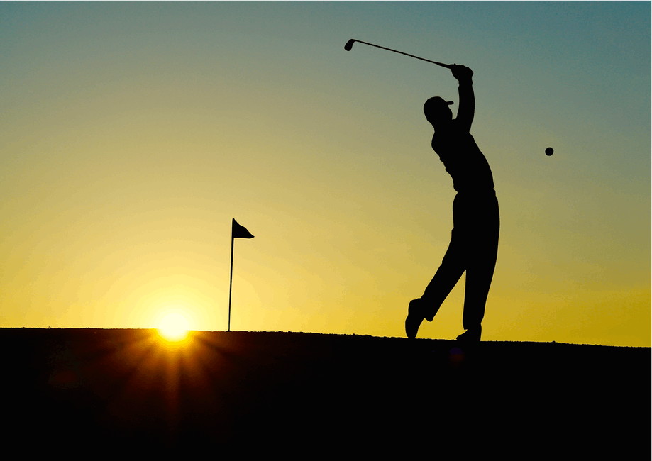 golfer hits shot in sunset