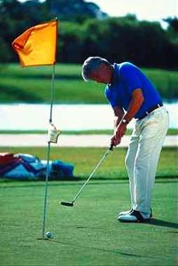 Blue-clad golfer sinking a putt with a large orange flag in the hole Blue-clad golfer sinking a putt with a large orange flag in the hole